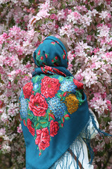 Russian fashionable girl in vintage Pavlovo Posad shawl. Pink flowers of blossoming apple-tree,...
