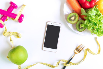 Selection of healthy food with fruits, vegetables, dumbbell ,tape measure and smart phone on white table background. Exercise for good health concept. Organic food, diet concept. Top view, copy space.