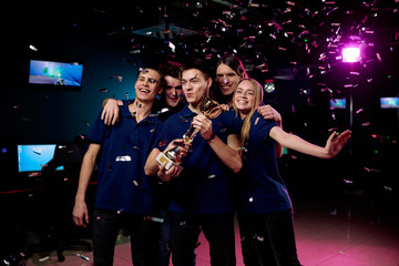 Group of five teenagers celebrating their victory in cybersports competition