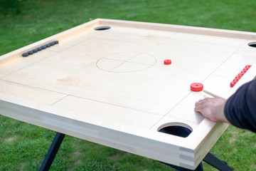 Person (only his hand on the picture) is playing Novuss game at the backyard