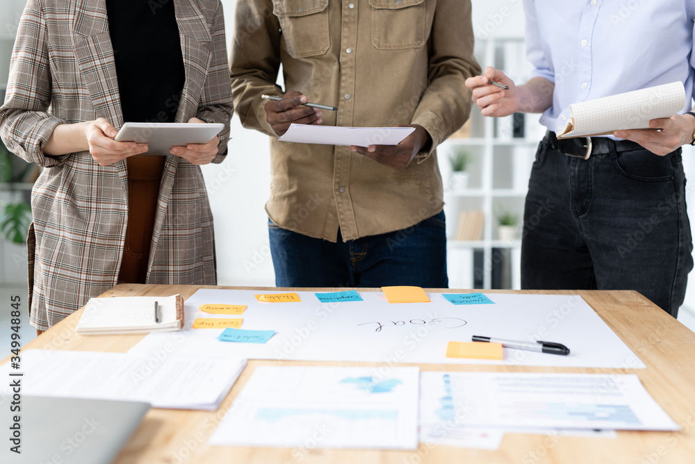 Aufkleber mid section of three colleagues standing in row by desk with papers