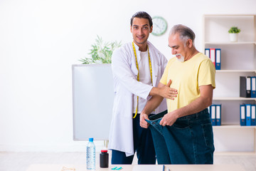 Fototapeta premium Doctor dietician and happy patient wearing large trousers