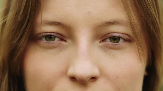 Natural beauty concept. Close up shot of caucasian woman with beautiful green eyes and frekles blinking and smiling