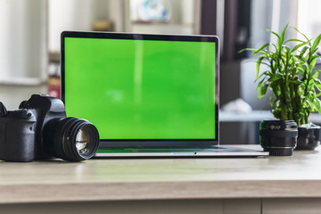 Laptop with mock-up green screen white background in office and Lovely plant in black pot