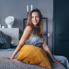 Young beautiful woman sitting on bed at home.