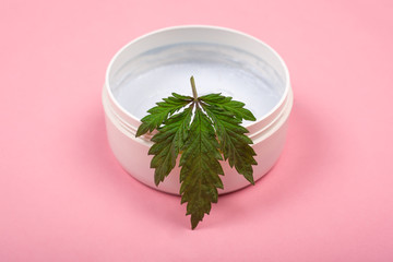 beauty cannabis cosmetics , natural marijuana cream and green leaf on beauty pink background