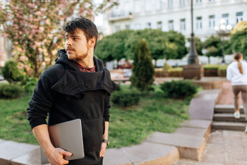Fototapeta premium Successful asian businessman walking in the street, holding a laptop in his hand