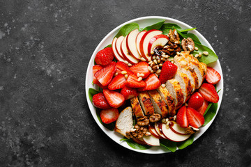Grilled chicken breast and strawberry salad with red apples, fresh spinach and nuts