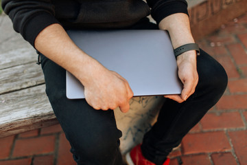 Young male working on his laptop computer in the city center. An independent person typing something in his document. chatting with friends over the internet, webcam