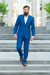 Bearded man in business centre. Confident brutal man walk street. Businessman in formal clothes. Business people. On his way to success. Walking down street. Mature hipster with beard on stairs