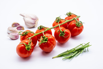 red cherry tomatoes with garlic cloves and rosemary on white background