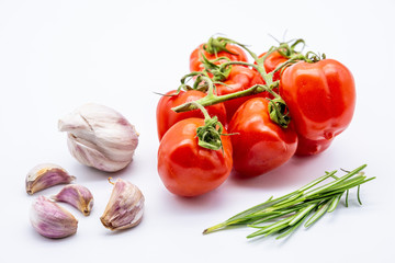 red cherry tomatoes with garlic cloves and rosemary on white background