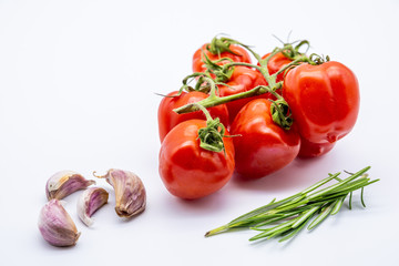 red cherry tomatoes with garlic cloves and rosemary on white background