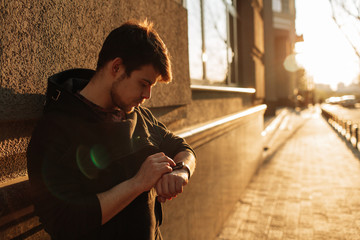 Man looking at his smartwatch in the city. Business concept.