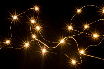 The lights of an electric garland on a black background, look like stars.
