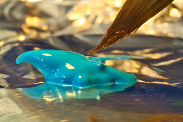 Fotografía macro de un pincel acercándose a un poco de pintura acrílica sobre un trozo de papel...