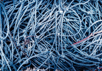 Navy-blue fishnets of rope knots and blue maritime background.