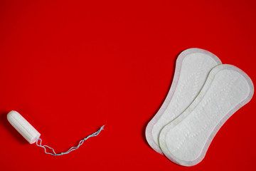 two white pads and a tampon during menstruation in women on a red background. gynecology and women's hygiene