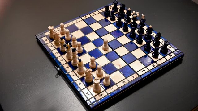 Making the first move. Moving pawn from E2 to E4. Playing with a beautiful white blue chessboard.