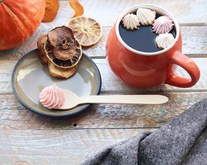 Cup of coffee, meringues, pumpkins, leaves, plaid on a window background, home comfort concept, Thanksgiving, autumn season