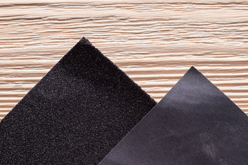 Several sheets of sandpaper with different grit on a wooden surface. It looks like a mountain landscape