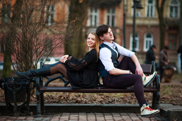 Loving young couple, guy and girl sitting on bench in city park