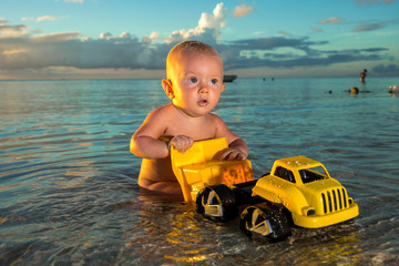 Little baby playing on the beach at ocean background