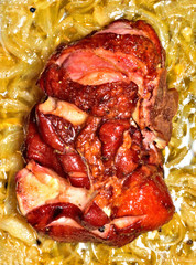 Roasted smoked pork knuckle on onion with garlic, honey and spices