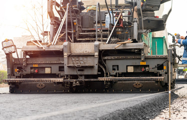 Paver machine is laying fresh asphalt on city road