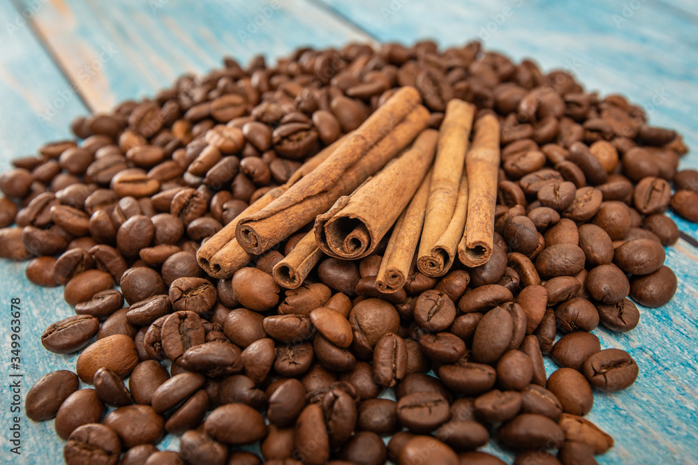 Wall mural cinnamon lies roasted coffee beans on a blue wooden background.