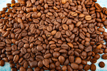 Roasted coffee grains on a blue wooden background, close-up.