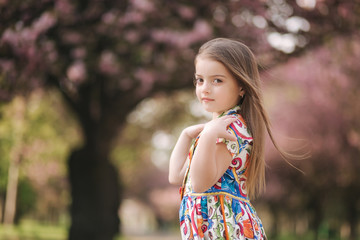 Young girl model poses to photographer. Female kid i beautiful dress outside