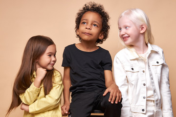 cute unusual albino and american kid girls attract the attention of afro boy sitting in the center, happy children, ethnic diversity - obrazy, fototapety, plakaty