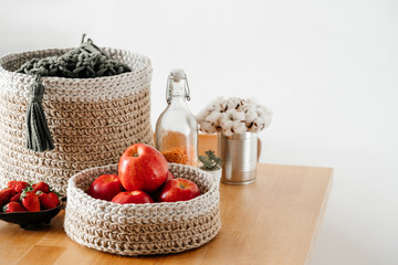 Wicker basket with red apples on a wooden table with strawberries. Timeless design and delicious natural vitamins.