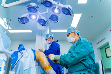 Surgeons working in operating room. Hospital background. Two male doctors at work. Circular shooting