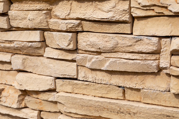 A fragment of wall decoration made of artificial yellow finishing stone for wall decoration. A diagonal position.