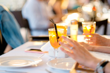 Cocktail party in outdoor cafe outdoor. Partying in a restaurant and toasting drinks. Happy young people with cocktails at pub in sunset.