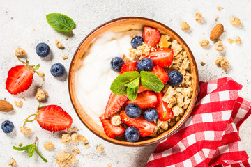 Greek yogurt granola with fresh berries on white stone table.