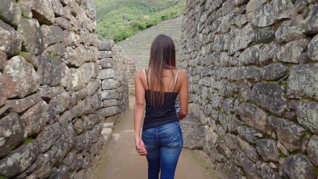 Slow motion of young woman walking through historic Peruvian old ruins - Machu Picchu, Peru