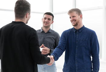 young men shaking hands in a creative office
