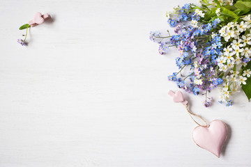 Forget-me-not flowers, lilac, bird cherry, decor heart on a wooden background for congratulations.