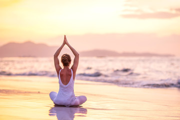 Woman practices yoga at seashore