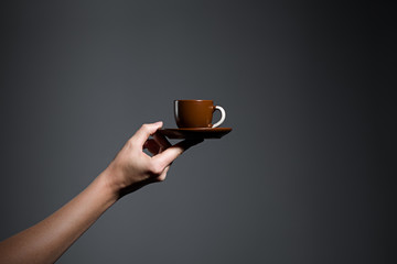 Hand holding a cup of coffee on grey background