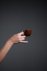 Hand holding a cup of coffee on grey background