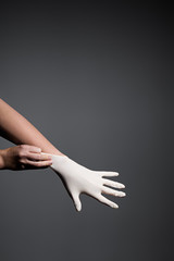 Woman's hand putting on white protective glove on gray background