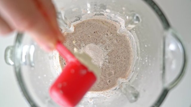 An electric blender, a mixer with a glass bowl, in which smoothies are prepared, porridge for whipping, pour protein powder, BCAA with a measuring spoon. Top view.