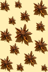 Fourteen anis stars of different sizes with sunny shadows create geometrical art composition on the light yellow background. Concept creative idea of art food pattern with spices