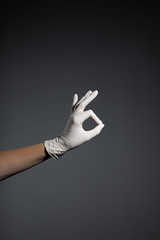 Womans hand in white protective gloves on gray background gesturing 