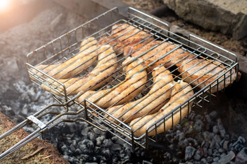 sausages lie on the grill and grilled at the stake. picnic in nature. bright highlight.