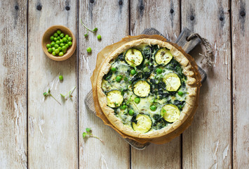 Obraz na płótnie Canvas Homemade rustic vegetable pie ( quiche) with spinach, zucchini and green peas